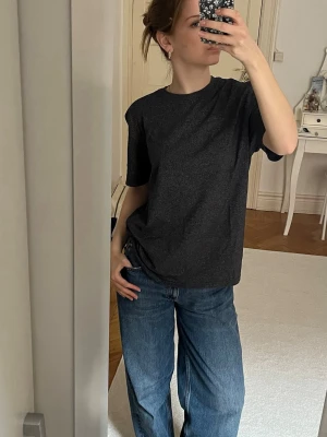 Mörkgrå basic t-shirt i bomull - En enkel och stilren mörkgrå t-shirt med normal passform och korta ärmar. Tillverkad i mjuk bomull som känns skön mot huden. Perfekt att matcha med jeans eller shorts för en avslappnad look.