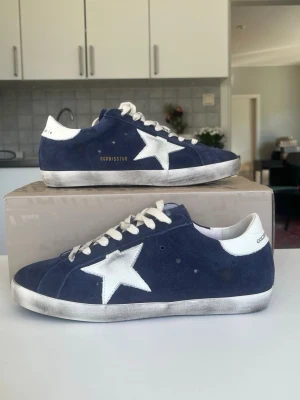 Mörkblå mocca Golden Goose - Säljer ett par riktigt fräscha golden Goose Superstar i mörkblå mocca. Som det ses på yttersidan är de lite använda som inte gick att få bort men inget man tänker på annars är ny ren gjorde och sen nästan helt nya ut. Storlek 43 Skriv vid minsta fråga👍 OBS Endast skor säljs