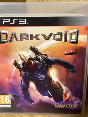 Dark Void till PS3 - Säljer spelet Dark Void till PlayStation 3. Ett actionfyllt sci-fi spel där du slåss mot utomjordingar i en parallell värld. Omslaget har en futuristisk hjälte med jetpack mot en orange och lila bakgrund. Spelet levereras i original plastfodral.