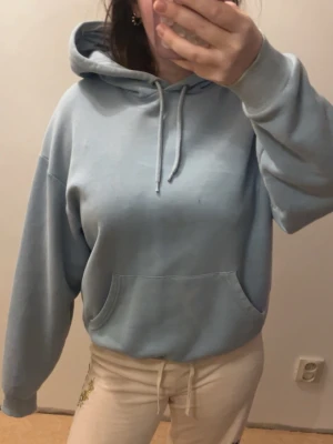 Ljusblå basic hoodie - Ljusblå hoodie med huva och dragsko, samt en stor magficka framtill. Hoodien har en avslappnad, vanlig passform och är tillverkad i mjukt sweatshirtmaterial. Perfekt för en chill och casual look.