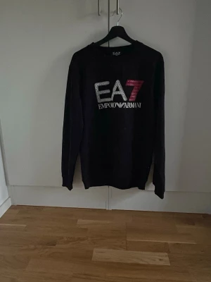 Svart EA7 Emporio Armani sweatshirt - Säljer en svart sweatshirt från EA7 Emporio Armani passar de med storlek M/L. Hör av dig vid minsta lilla fundering!