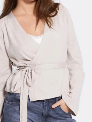 Beige omlottkofta med knytband - Trendig beige omlottkofta med långa ärmar och knytband i midjan. Koftan har en djup V-ringning och är tillverkad i ett mjukt, tunt material som ger en avslappnad men stilren look. Perfekt att matcha med jeans eller kjol.