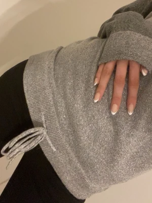 Glittrig grå tröja med knytband - Säljer en glittrig grå tröja med långa ärmar och rund hals. Tröjan har ett snyggt knytband i nederkanten och är perfekt för dig som vill sticka ut lite extra. Tröjan är köpt för ett tag sedan men har inga tecken på användning där av priset💗 OBS pris går att diskutera 