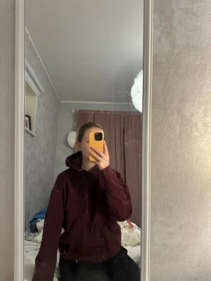 Vinröd hoodie med huva och ficka - Mysig vinröd hoodie med klassisk huva och dragsko samt en stor magficka framtill. Hoodien har en avslappnad passform och långa ärmar. Perfekt för chill dagar eller när du vill ha något bekvämt.