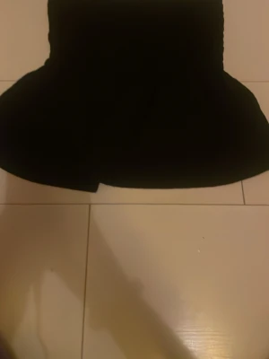 Svart bandeau topp från Gina Tricot - Säljer en svart bandeau topp från Gina Tricot. Toppen är axelbandslös och har en enkel, stilren design som passar perfekt till många olika outfits. Materialet är mjukt och stretchigt för en bekväm passform.