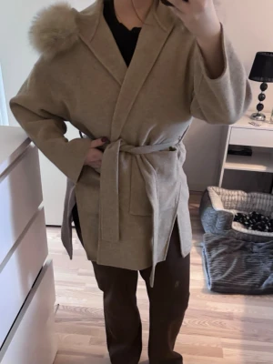 Kappa - Kappa med pälskrage från Fur Stockholm modell Alicia. Kappan är i mycket bra skick men är lite lös i en söm som enkelt går att fixa. 