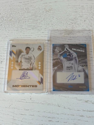 Autografkort Real Madrid Morientes & Salgado - Två samlarkort från Topps med autografer av Morientes och Salgado i Real Madrid. Kort i plastfickor, ett i guldvitt och ett i blåsvart design. Båda visar spelarna i matchtröja och har Real Madrid-logga. Salgado-kortet är numrerat 103/150.