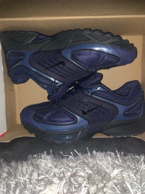 Nike P-6000 mörkblå sneakers - Nike P-6000 sneakers i mörkblå mesh och syntetmaterial med svarta detaljer och svart sula. Skorna har en sportig design med tydliga linjer och små Swoosh-loggor på sidan. Perfekta för dig som gillar en retroinspirerad look.