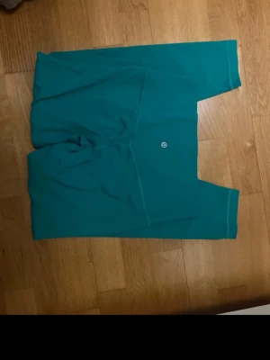 Turkosa leggings från Lululemon - Snygga turkosa leggings från Lululemon med hög midja och stretchigt material som sitter skönt. Perfekta för träning eller chill. Diskret logga på benet och sömlös design för en clean look.typ trekvart 