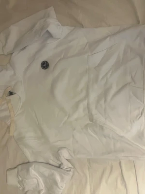 Vit hoodie från Sir Raymond Tailor - Säljer en vit hoodie från Sir Raymond Tailor med rund logga på bröstet där det står 'Los Angeles'. Hoodien har en stor magficka och ribbade muddar vid ärmsluten. Perfekt för en chill och avslappnad stil.