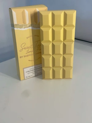 Sweet Tooth Lemon Parfym 75 ml - Unik parfym i en ljusgul flaska formad som en chokladkaka från Sabrina Carpenter. Doften heter Sweet Tooth Lemon och flaskan rymmer 75 ml. Förpackningen matchar flaskans design och har en modern, lekfull känsla. Köptes igår.