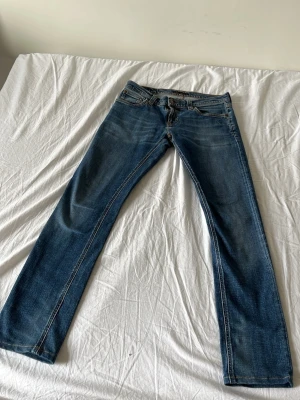 Blå raka jeans med slitningar - Ett par klassiska blå jeans med raka ben och lätt slitna detaljer.  W31 L32. 