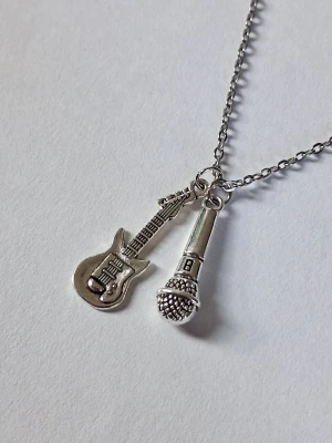 Halsband med gitarr och mikrofon - Snyggt halsband med två detaljerade berlocker: en elgitarr och en mikrofon. Perfekt för dig som älskar musik och vill ha en unik accessoar som sticker ut. Kedjan är tunn och smidig men slitstark och berlockerna har coola detaljer. Materialet rostfritt stål. 
