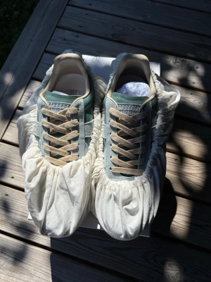 Ljus blå maison margiela gats - Snygga sneakers i färgen ljusblå med beige snören och detaljer. Ovandelen är i mocka och slätt material, och sulan är i gummi. Klassisk låg modell med stilren design som passar till många outfits.