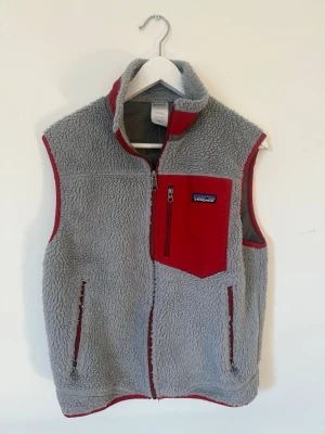 Patagonia - Retro Fleeceväst - Mysig grå fleeceväst från Patagonia med röda detaljer och dragkedjor. Använd endast ett fåtal gånger och perfekt nu inför hösten. Storlek S men passar även XS. 