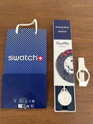 AP x Swatch Royal Pop Huit (Vit) - Hejsan! Säljer min Swatch Royal Pop klocka i vitt med färgglada detaljer på urtavlan.   Denna i vitt utförande är en av de mest ovanliga AP x Swatch modellen.   Skickar med ett armband i vit plast (om man ej vill bära klockan i snöret som redan sitter)  Bvsa! Skickas!