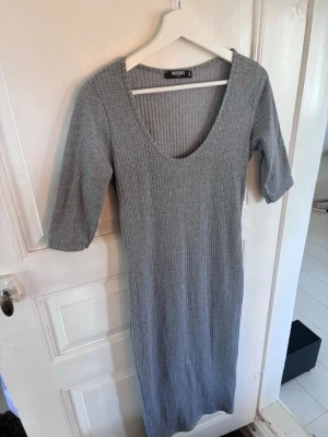 Grå ribbad långklänning Missguided - Snygg grå långklänning från Missguided med ribbad struktur och djup v-ringning. Klänningen har halvlånga ärmar och är i en mjuk, stretchig bomullsblandning som sitter bekvämt och följer kroppen.