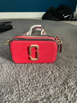 Röd axelväska Marc Jacobs - Säljer denna jätte snygga axel/handväska med märket Marc Jacobs! ⚠️OBS⚠️ Den är inte äkta! MEN! Den är i ett jätte fint skick och jag väldigt bra kvalitet. (Använd max 3 gånger) 