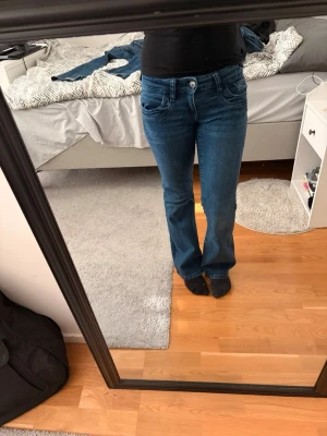 Blå bootcut jeans med låg midja - Säljer ett par blå bootcut-jeans från Gina Tricot Young i storlek 158. Passar även dig som vanligtvis har XXS eller XS (petite). Sitter lågt i midjan (low waist/low rise) och har en smickrande bootcut-passform. Jättefint skick utan några synliga defekter. 