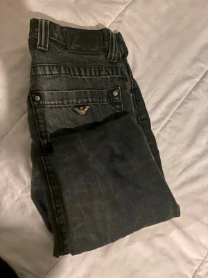 Svarta jeans från Armani Jeans - Säljer ett par svarta jeans från Armani Jeans med klassisk femficksdesign och silverfärgade detaljer. Jeansen har en rak passform och är tillverkade i denim med en snygg tvätt. Perfekta för dig som vill ha en stilren och tidlös look.