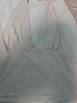 Beige halterneck topp Gina Tricot - Säljer en beige halterneck topp från Gina Tricot. Toppen har djup v-ringning och knyt i nacken, vilket ger en snygg och trendig look. Perfekt för varma dagar eller sommarens alla tillfällen.