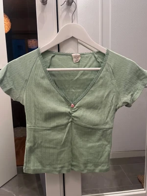 Grön topp  - Supersöt grön topp i bomull & pointelle från urban outfitters. Knappt använd, mer piggelingrön i verkligheten 