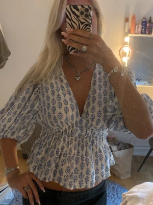 Blus H&M - V-ringad vit och blå blus från H&M med puffiga trekvartsärmar, figursydd och liten i storleken sitter som S/M som jag har i vanliga fall 
