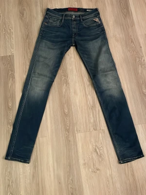 Replay Anbass Mörkblå slim fit jeans - Snygga mörkblå slim fit jeans med slitningar och tvättade detaljer. Klassisk femficksmodell med bälteshällor och knappgylf. Jeansen har en modern passform och är perfekta för en trendig vardagslook. Perfect för grischstil! SHIPPING ON SAME DAY!