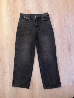 Svarta raka jeans med hög midja - Säljer ett par svarta jeans med rak passform och hög midja. Jeansen har klassisk femficksdesign och knappgylf. Perfekta för en avslappnad och trendig look. Materialet är denim i bomull.