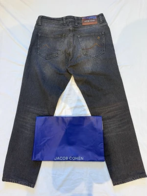 Grå jeans från Jacob Cohën - Midje mått 41cm. Midja till byxbens slut 91cm. Låt 28,5 cm. Jacob Choën jeans påse följer med. Skriv vid frågor! 