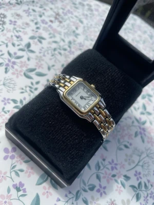 Sekonda silver- och guldfärgad klocka - Stilren klocka från Sekonda med fyrkantig urtavla, romerska siffror och tvåfärgad länk i silver och guld. Klassisk design som passar till många stilar. Levereras i originalask. Pris går att diskuteras och mer information finns