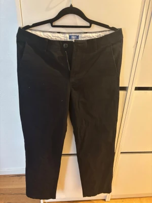Svarta chinos från Jack & Jones - Snygga svarta chinos från Jack & Jones med klassisk rak passform. Byxorna har sidofickor, bälteshällor och två bakfickor med knapp. Tillverkade i ett mjukt bomullsmaterial som ger en skön känsla och stilren look. NYA MED PRISLAPP!!! Nytt pris 349kr!!