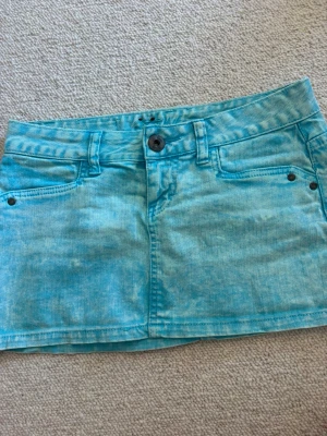 Turkos kort jeanskjol från Fishbone - Säljer en turkos kort jeanskjol från Fishbone med klassisk femficksmodell, bälteshällor och knappstängning fram. Kjolen har en tvättad look och är perfekt för dig som gillar en avslappnad och trendig stil.💓