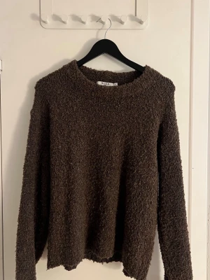 Stickad tröja  - Mysig brun stickad tröja från NA-KD i storlek XS. Tröjan har en fluffig, texturerad yta och rund halsringning. Perfekt för kalla dagar och enkel att matcha med jeans eller kjol.