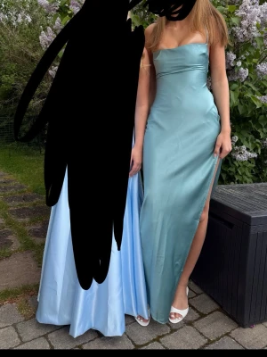 Ljusblå långklänning med slits - Elegant ljusblå långklänning i figurnära modell med axelbandslös design och hög slits på sidan. Klänningen har en slät, glansig yta som ger en exklusiv känsla och passar perfekt till speciella tillfällen. Enkel men stilren look. OBS de är två fläckar på framsidan som syna på bild 3!❤️