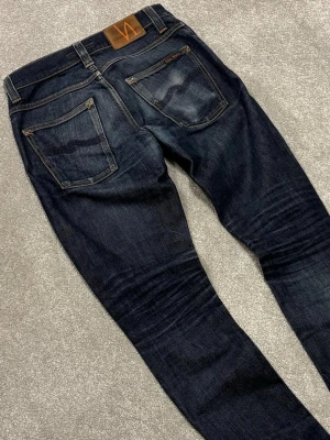 Nudie Jeans Grim Tim - Nudie Jeans | Modell: Grim Tim | Skick 9/10 mycket bra | | Nypris ca 2500kr | Mitt pris 799kr | Midja: 38,5cm | Ytterbenslängd: 105cm | Benöppning: 16cm | Lår: 28cm | Kom gärna pm vid frågor eller funderingar | Priset kan diskuteras.