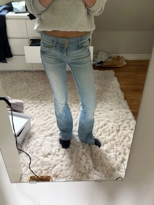 Ljusblå bootcut jeans  - Säljer ett par ljusblå bootcut jeans med dubbla knappar i midjan och klassiska fem fickor. Jeansen har en snygg tvätt och lätt utsvängda ben. Perfekta för en avslappnad outfit till sommaren!☀️⛱️