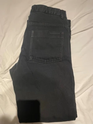 Prada jeans  - Säljer ett par svarta Prada jeans i storlek 33/32 med raka ben och klassisk femficksdesign. Jeansen har en enkel look utan slitningar eller dekorationer, perfekta för en clean och stilren outfit. Materialet känns mjukt och stretchigt för extra komfort.