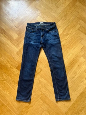 Mörkblå raka jeans  - Snygga mörkblå jeans från Nudie Jeans med klassisk femficksmodell och raka ben. Jeansen har kontrastsömmar och en patch i läderimitation bak i midjan. Tillverkade i slitstark denim, perfekta för en avslappnad och stilren look.