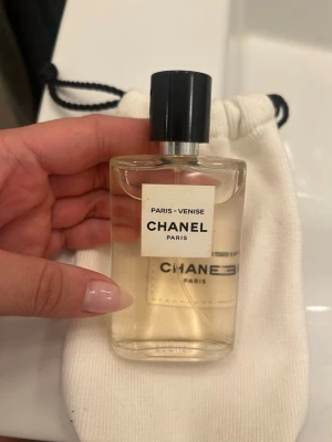 Chanel Paris-Venise Eau de Toilette - Elegant parfym från Chanel, Paris-Venise, i en genomskinlig glasflaska med svart lock och vit etikett. Doften är inspirerad av Venedig och Paris och kommer i en stilren, rektangulär flaska. Perfekt för dig som gillar exklusiva och klassiska dofter. 125 ML ca 85%. Nypris 1800kr. Originalpåse medföljer. Kan även mötas upp i Stockholm 