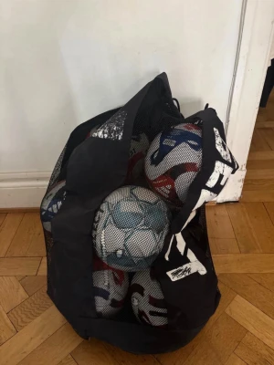 Nätväska med fotbollar - Säljer en svart nätväska fylld med flera fotbollar i vitt, blått och rött mönster. Perfekt för träning eller matcher när du behöver ta med flera bollar. De är 6 addias trio competion en select och en em boll, 