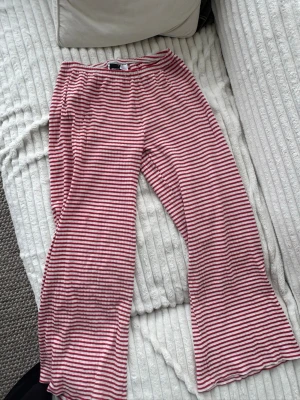 Randiga Gina byxor rött och vitt  - Mysiga loungebyxor med röda och vita horisontella ränder. Byxorna har en avslappnad passform med resår i midjan och vida ben. Perfekta för chill dagar hemma eller när du vill vara extra bekväm.