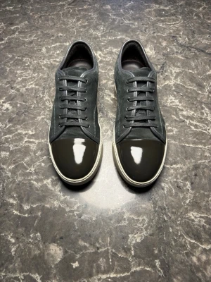 Lanvin - Säljer ett par otroligt snygga skor från det exklusiva märket Lanvin! Skorna är i mycket bra skick, skulle säga ungefär 9,8/10. Nypris ligger på över 4000kronor men vi säljer våra för endast 2299 och kan gå ner i pris ännu mer vid snabb affär! Skorna är gråa och mörkgröna. Skorna är i storlek UK 12 vilket motsvarar 46 men är stora i storleken så passar mer 47. Skriv gärna ifall det är några funderingar, allt bästa SkoKapet