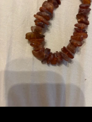 Brunt bärnstenshalsband med pärlor - Unikt halsband med oregelbundna pärlor i brun bärnsten. Pärlorna har en naturlig, rå form och ger ett bohemiskt och jordnära intryck. Perfekt för dig som gillar naturmaterial och vill ha ett smycke som sticker ut.