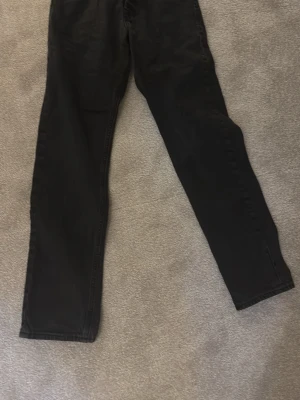Svarta raka jeans - Säljer ett par svarta jeans med rak passform och klassisk femficksdesign. Jeansen har en enkel look och passar perfekt till en avslappnad stil. Materialet känns som bomull med lite stretch för extra komfort. Dom är 28/32