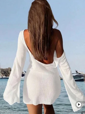 Vit strandklänning med vida ärmar - Säljer en snygg vit strandklänning i tunt, transparent material. Klänningen har långa, vida ärmar och en djup rygg som ger en avslappnad och trendig look. Andvänd endast en gång!🤗💕