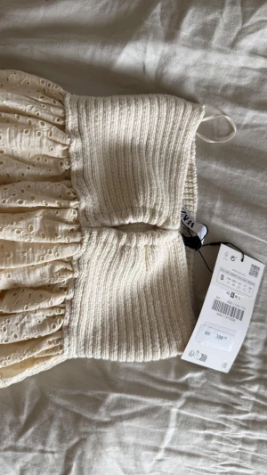 Vit broderad kjol från Zara - Jättefin vit kjol från Zara med ribbad, stretchig midja och broderade hål i kjoltyget. Kjolen har en luftig och somrig känsla, perfekt till varma dagar. Materialet är mjukt och bekvämt, och designen ger en romantisk vibe.