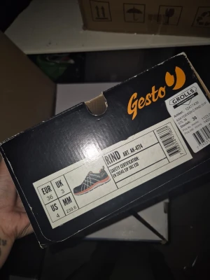 Gesto Rind skyddssko svart/orange - Skyddssko från Gesto, modell Rind, i svart med orange detaljer och robust gummisula. Skon har säkerhetscertifiering EN 20345 S1P SRC ESD och är designad för att vara slitstark och bekväm. Perfekt för dig som vill ha en snygg och funktionell arbetssko.