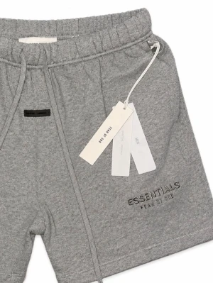 Grå Essentials shorts med snörning - Snygga grå shorts från Fear of God Essentials med broderad logga på benet. De har elastisk midja med snörning och är gjorda i mjuk bomull. Perfekta för chill dagar och enkel streetwear-stil.