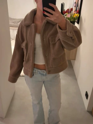 Beige teddyjacka med fickor - Säljer en beige teddyjacka med krage och två stora bröstfickor. Jackan är kortare i modellen och har tryckknappar framtill🌸